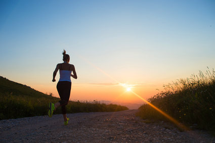 woman running outdoor on a mountain road at summer sunset